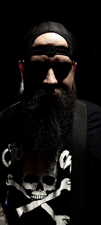 Shadowed portrait of Nate Laff with a backwards cap and long beard, eyes hidden in darkness